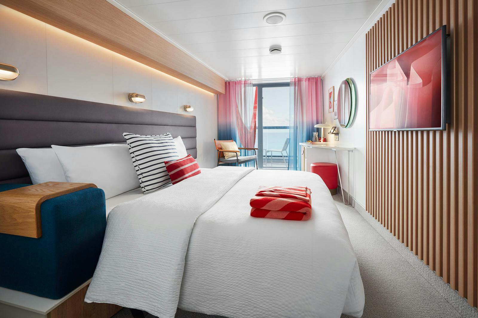Virgin Voyages Sea Terrace interior with a bed, seating, and doors opening onto the balcony.