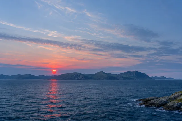 Editorial artwork of open northern Norwegian water, distant bare hills, and a small red sun. No aurora or ice fields.